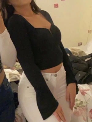 Svart långärmad topp - Trendig svart topp med lång ärm och snygg v-ringning. Toppen har en figurnära passform och är tillverkad i ett stretchigt material som sitter bekvämt. Perfekt att matcha med höga jeans för en stilren look.