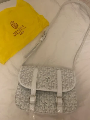 Vit axelväska från zara - Snygg vit axelväska från Zara med klassiskt mönster och silverfärgade spännen. Väskan har justerbar axelrem och två dekorativa remmar framtill. Tillverkad i canvas med detaljer i läder. Perfekt för dig som vill ha en stilren och trendig accessoar.