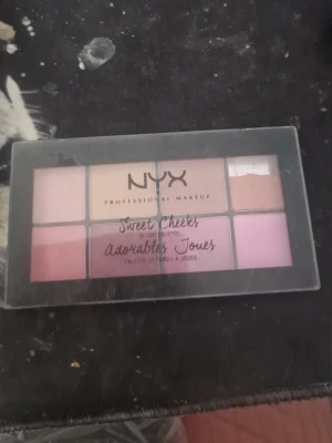 NYX Sweet Cheeks Rougepalett - NYX Sweet Cheeks Blush Palette med åtta olika nyanser i rosa, nude, lila och persika. Paletten har en rektangulär form och genomskinligt lock. Perfekt för att skapa olika blush-looks med både matta och skimrande färger.