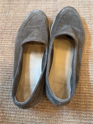 Grå mockaloafers från Myrqvist - Snygga loafers i grå mocka från  Myrqvist Skorna har en klassisk, stilren design med rundad tå och vit sula. Perfekta för dig som gillar en clean och avslappnad look. Materialet är mjukt och ger en lyxig känsla. Nypris 2500