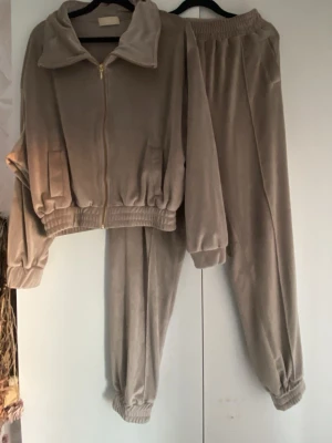 Beige velour loungewear-set - Mysigt loungewear-set i beige velour med dragkedja på tröjan och resår i midja och benslut. Setet består av en långärmad ziptröja med krage och matchande byxor med fickor och elastisk midja. Perfekt för chill dagar hemma❣️