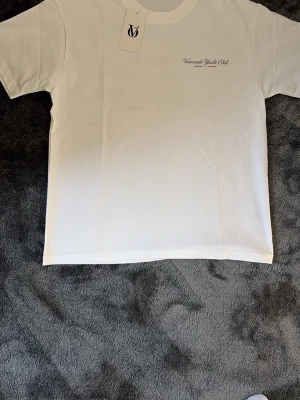 Vit Voronado Yacht Club t-shirt - Vit t-shirt från Voronado Yacht Club med tryck på bröstet och stor Saint Tropez-båtgrafik på ryggen. Klassisk passform och rund hals. Perfekt för en chill och stilren look.
