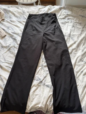 Svarta vida byxor från BikBok - Snygga svarta byxor från BikBok i storlek 38. Byxorna har hög midja och vida ben, vilket ger en trendig och avslappnad look. Perfekta att styla med crop tops eller oversized tröjor. Materialet är mjukt och följsamt för extra komfort.