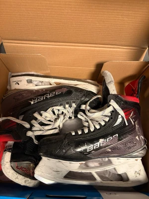 Bauer Vapor hockeyskridskor svart/röd - Säljer ett par Bauer Vapor hockeyskridskor i svart och rött med vita detaljer. Skridskorna har klassisk snörning, robust yttermaterial och bekväm vaddering på insidan. Perfekta för dig som vill ha bra grepp och kontroll på isen.