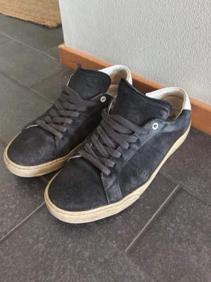 Svarta sneakers med vit sula - Stilrena svarta sneakers med vit sula och svarta skosnören. Skorna har en klassisk låg modell och är tillverkade i mockaliknande material. Insidan är ljus . Perfekta för en avslappnad streetstyle.