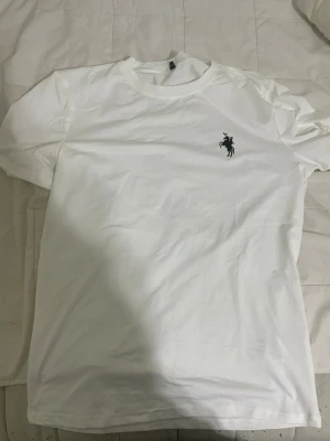 Vit t-shirt Polo Ralph Lauren - Snygg vit t-shirt med rund hals och korta ärmar. På bröstet finns en Polo Ralph Lauren logga. Perfekt basic-plagg som funkar till allt. Tillverkad i mjuk bomull för skön känsla hela dagen.