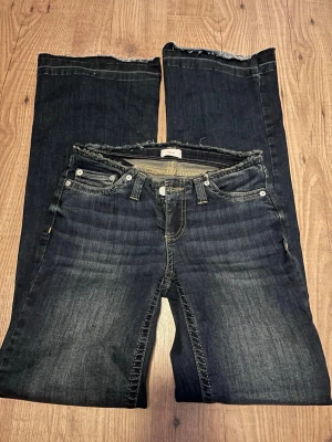 Mörkblå no waist jeans från Nelly  - Snygga mörkblå no waist jeans med raka ben och fransiga kanter både nertill och vid midjan. Jeansen har klassisk femficksdesign, kontrastsömmar och låg midja. Perfekta för en avslappnad och trendig look. Använda fåtal gånger säljer pga för små!