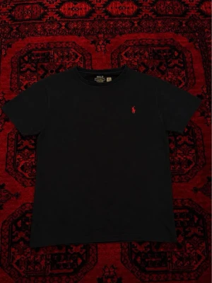 Svart t-shirt från Polo Ralph Lauren - Skick, 8/10 inga defekter. Storlek M men passar bättre om man har EU S då den är 63 cm på längden vilket motsvarar EU S. Tvättas och fräschas upp innan frakt! Pris går att diskutera vid bundleköp / snabbaffär 💯🤝