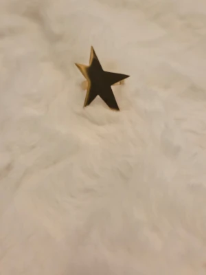 Guldfärgad ring med stjärnform - Cool ring i guldfärg med en stor stjärna som motiv. Ringen har en blank yta och är tillverkad i metall. Perfekt accessoar för dig som vill sticka ut med en unik och trendig detalj.Köpt på plick🥰 den var tyvärr lite stor på mig så det är därför jag säljer den❣️vet ej storlek🥹