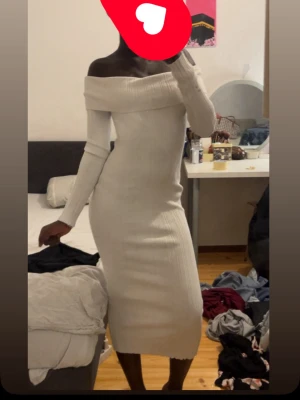 Vit ribbad offshoulder långklänning - Snygg vit långklänning med ribbad struktur och offshoulder-design. Klänningen är figurnära och har långa ärmar, perfekt för dig som gillar en stilren och trendig look.
