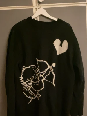 Svart stickad tröja med amor-motiv - Stickad tröja med Amors pilbåge motiv, passar M-L 