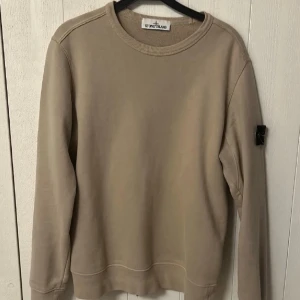 Stone Island Sweatshirt  - Klassisk Stone Island-sweatshirt i beige färg med ikonisk badge på ärmen. Storlek S, men passar mer som M. Stilren, lättmatchad och perfekt till vardags/streetwear.  QR-kod finns som äkthetsbevis. Skick enligt bilder.