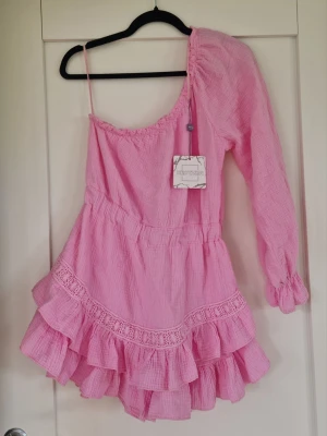 Rosa oneshoulder klänning med volanger - Nedre delen av klänningen är "inbyggda" shorts Den är one size men är som en M Från New CVLTR med Prislappen kvar  Kolla gärna på mina andra annonser har rensat min garderob 🙈