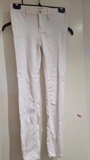 Vita skinny jeans från fb sister S - Snygga vita skinny jeans från FB Sister med klassisk femficksdesign och silverfärgad detalj vid hällan. Jeansen har smal passform och är tillverkade i ett stretchigt denimtyg för extra komfort.