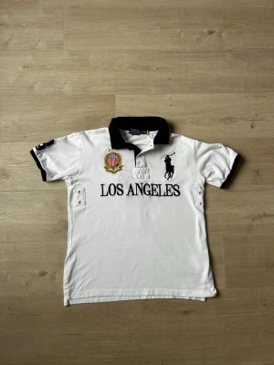 Vit Ralph Lauren Piké Big Pony Los Angeles Storlek L - Mycket fin tröja i vit färg. Tröjan är i mycket bra skick och sparsamt använda. |  Äkta som allt annat jag säljer! ✅ |  Storlek: L | Skick: Mycket Bra Skick - Tyvärr 2 väldigt små fläckar men inget som syns (SE SISTA 2 BILDER) | Färg: Vit | Märke: Ralph Lauren | Modell: Tröja |   Hör gärna av dig vid frågor så svarar jag så fort jag kan! 😁