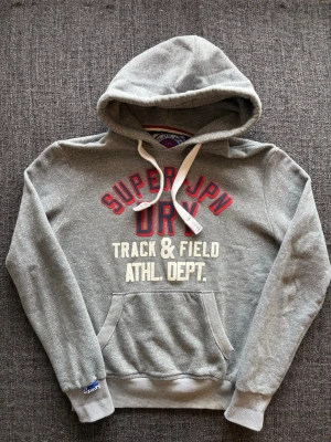 Superdry hoodie ~ vintage   - Sjukt eftertraktad Superdry hoodie i grå – vintage modell, sjukt sällsynt, stl M. Fint skick och sitter riktigt bra 🌿  Kan även gå ner lite i pris vid snabb affär ✌️ Skickas inom 24h 📦