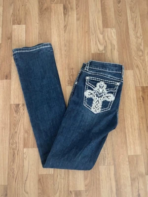 Mörkblå Miss Me jeans med brodyr - Snygga mörkblå jeans från Miss Me/la idol USA med straight ben och dekorativa broderier i vitt på bakfickorna. Jeansen har kontrastsömmar och klassisk femficksdesign. Använda en gång då dom inte riktigt var min stil för referens är jag 173 och dom är bra i längden, inte alls korta. Jag är storlek M/38 och får i mig dom, dom är lite tajta på låren då jag tränar mycket lår 🥰  ge jätte gärna bud 