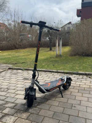 Kukirin el-scooter svart/orange - Säljer en el-scooter av modellen Kukirin, svart med orange detaljer. Scootern har bred fotplatta med mönster, robust ram i metall och stora hjul för extra stabilitet. Utrustad med stöd, handtag med grepp och tydlig display på styret. Kört under 200km med den. 3 dagar.
