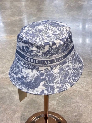 Christian Dior bucket hat blåvit - Snygg bucket hat från Christian Dior i blått och vitt med ett detaljerat mönster och tydlig logga runt hatten. Perfekt accessoar för att lyfta din stil med en exklusiv touch. Tillverkad i bomull för en bekväm känsla.
