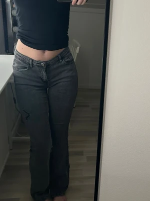 Lågmidjade jeans  - Mörkgrå lågmidjade jeans i storlek S, mjukare jeans material, stretchiga. Detaljer på framsida lår. Fattas på sista bilden där man drar igenom skärp 