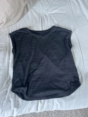 Svart ärmlös träningstopp - En stilren svart ärmlös linnetopp med rund halsringning. Toppen har en enkel och avslappnad passform, perfekt att matcha med jeans eller kjol. Materialet känns mjukt och lätt mot huden.