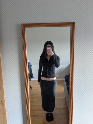 Svart lång stickad kjol  - Säljer en grå ribbstickad långkjol från Uniqlo i storlek XS. Kjolen är tillverkad i mjukt ullmaterial och har en klassisk, rak passform som sitter snyggt i midjan. Pris kan diskuteras🌸