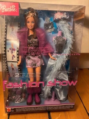 Barbie Fashion Show 2004 docka i box - Barbie Fashion Show-docka från Mattel ca 2004 med klassisk Y2K-look och glamorös modeinspirerad styling. Dockan är oöppnad och kvar i originalförpackning (NRFB/New in Box).  Innehåller flera tillbehör samt extra outfit på provdocka. Modellen har även ljuseffekt i toppen, vilket var en populär detalj under tidigt 2000-tal.  Perfekt för Barbie-samlare, nostalgiker eller dig som älskar Y2K-estetik och retro mode.  Skick: Oöppnad i originalbox. Fint vintage/samlarskick 