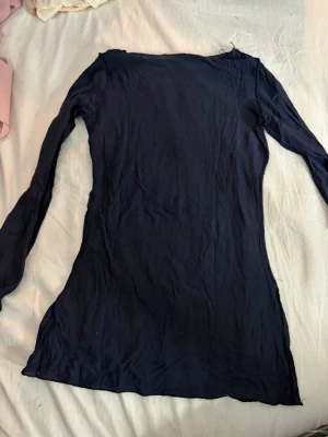 Intemissmi Mörkblå långärmad topp - Intemissmi tröja En enkel och stilren mörkblå långärmad topp med rund halsringning. Modellen är figurnära och passar perfekt till jeans eller kjol. Tunt och mjukt material som känns skönt mot huden.