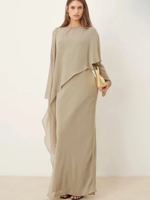 Beige långklänning med asymmetrisk volang - Elegant beige långklänning med asymmetrisk volangdetalj och lång ärm. Klänningen har en flowy siluett och är tillverkad i ett lätt, svepande material som ger en exklusiv känsla. Perfekt för dig som gillar stilrena och unika plagg. Helt ny med prislappen kvar. Perfekt för hijabisar och modest tjejer!