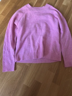 rosa stickad tröja - Mysig rosa stickad tröja med rund halsringning och ribbade muddar vid ärmslut och nederkant. Perfekt för lager-på-lager och enkel att matcha med jeans eller kjol. Tröjan har en avslappnad passform och är superbekväm.
