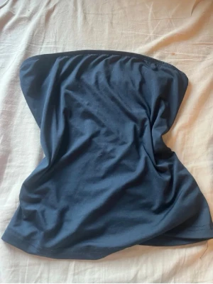 Blå bandeau tubtopp - En enkel svart halsduk i ett mjukt och stretchigt tyg. Halsduken har en klassisk, stilren design och passar perfekt att svepa runt halsen för extra värme. Lätt att matcha med olika jackor och outfits.