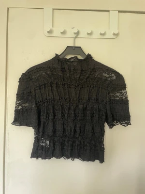 Svart spetsblus med volanger - Svart blus passar XS/S