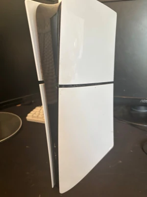 PlayStation 5 spelkonsol - Säljer en PlayStation 5 SLIM  med futuristisk design i vitt och svart. Konsolen har en slimmad, stående form och är tillverkad i plast. Perfekt för gaming med HDMI och USB-portar på baksidan. Grym prestanda för både nya och klassiska spel. Kontroll ej ingår hdmi cabel o ström cabel ingår 