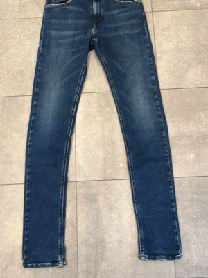 Mörkblå skinny jeans med slitningar - Snygga mörkblå skinny jeans med lätt slitna detaljer och klassiska fem fickor. Jeansen har en smal passform och normal midja. Perfekta för en trendig och avslappnad look. Den har gått sönder lite på replay tagen på baksidan men går att sy fast annars är de inga andra defekter! Om de är nått är de bara att höra av sig!