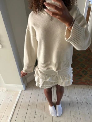 Vit volangkjol i jeans tyg  - Supersöt vit kortkjol med volanger och råa kanter. Kjolen har klassiska jeansdetaljer som fickor och knapp framtill, vilket ger en cool och trendig vibe. Perfekt att styla med en stickad tröja eller crop top för en fräsch look.
