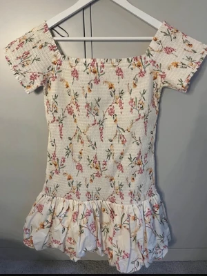 Blommig kortklänning med volang - Säljer denna populära klänning från H&M som inte säljs längre. Klänningen är endast använd 1 gång och är därför i väldigt fint skick. 