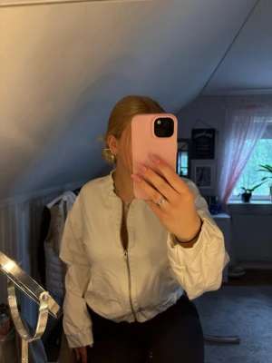 Vit kofta från 157 - Säljer en vit kofta från lager 157 med dragkedja framtill och ribbade muddar vid hals, ärmslut och nederkant. Kofta  har en clean look och passar perfekt till jeans eller kjol. Materialet känns lätt och bekvämt.