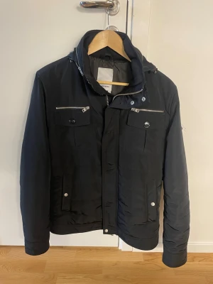 J.Lindeberg jacka  - Tja säljer denna gamla sällsynta jacka från J.linderberg modell Bailey Recy Poly Jacket storlke M skick 9/10 ända som är defekt är loggan på armen kolla bild 4 utöver de är den felfri från skavanker 😊🤞🏽vid frågor eller om bättre bilder hör gärna av dig 😁Priset ej hugget i sten 🪨 