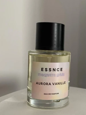 Aurora Vanille parfym från Essnce - Aurora Vanille Eau de Parfum från Essnce x Margareta Grääs. Flaskan är cylindrisk i genomskinligt glas med svart lock och en ljus etikett med text. Doften har en tydlig vaniljkaraktär och flaskan har en stilren, modern design. Helt ny