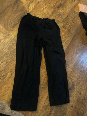 Svarta linnebyxor från Kappahl XS - Säljer ett par svarta linnebyxor från Kappahl i storlek XS. Byxorna har rak passform och resår i midjan för extra komfort. Perfekta till sommaren och lätta att matcha med olika toppar. Materialet är svalt och luftigt linne.