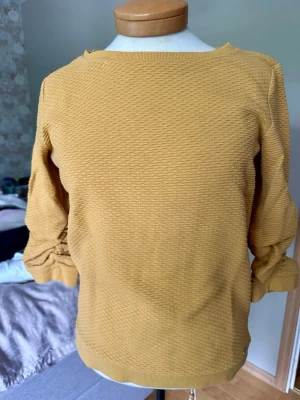 Gul strukturerad tröja XS - Säljer en gul Tom Tailor tröja med snygg struktur och rund hals. Tröjan har halvlånga ärmar och ribbade muddar vid ärmslut och nederkant. Perfekt för dig som gillar en enkel men trendig stil. Materialet känns mjukt och bekvämt.
