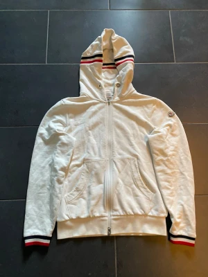 Moncler zip upp - Vit Moncler hoddie strl m passar m/s den har en liten slitning som man ser på bild 2 men utöver det så är den i bra skick