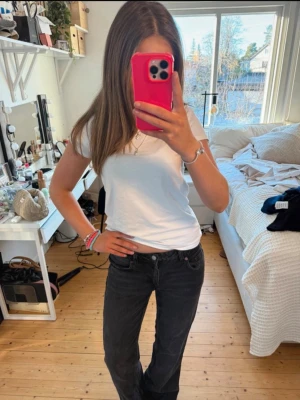 Zara jeans - Säljer ett par svarta jeans med rak passform och låg midja. Jeansen har klassisk femficksdesign och knappgylf. Perfekta till en enkel t-shirt eller hoodie för en avslappnad look.