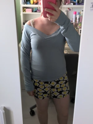 Ljusblå offshoulder topp - Säljer en ljusblå långärmad topp med offshoulder-design och v-ringad hals. Toppen har en enkel och stilren look, perfekt att matcha med olika outfits. Materialet känns mjukt och stretchigt för en bekväm passform. Står L men skulle säga att det är en S