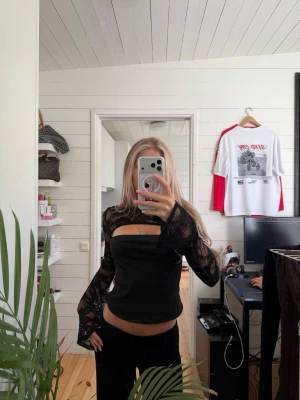 Svart långärmad spets topp - Trendig svart långärmad topp med transparent spets och croppad passform. 