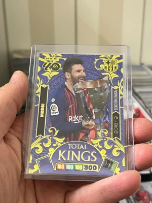 Panini Adrenalyn XL Total Kings kort Lionel Messi - Säljer ett Panini Adrenalyn XL Total Kings samlarkort från 2018-19 med fotbollstema. Kortet har färgstark design i blått och gult, visar en spelare med pokal Lionel Messi och har detaljer som klubbmärke och stats. Perfekt för dig som gillar samlarkort och fotboll.