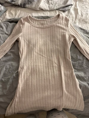 Ljusbeige ribbad långärmad topp - Säljer en ljusbeige ribbad långärmad topp med rund halsringning. Toppen har en figurnära passform och är tillverkad i ett mjukt, stretchigt material som känns skönt mot huden. Perfekt att styla med jeans eller kjol för en enkel och snygg look.
