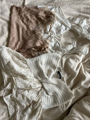 Tre somriga toppar i beige och vitt - Säljer tre olika toppar: en beige ribbad topp med spetsdetaljer, en vit volang topp och en vit stickad topp med broderade detaljer. Perfekta för varma dagar. 