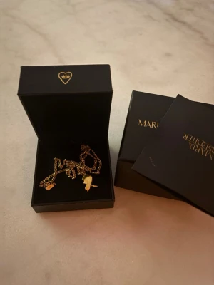 Maria Nilsdotter halsband  - Säljer mitt Maria Nilsdotter halsband då det inte längre kommer till användning. Kommer i original ask och halsbandet är i fint skick med lite små slitningar som inte syns när man har på sig det. 