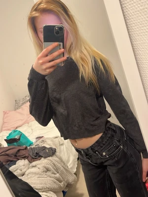 Mörkgrå croppad tröja - En enkel och stilren mörkgrå croppad tröja med långa ärmar och ribbade muddar. Perfekt för en avslappnad look och passar bra till jeans eller andra byxor.